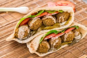 Falafel in half Pita sandwiches, on a wooden table.