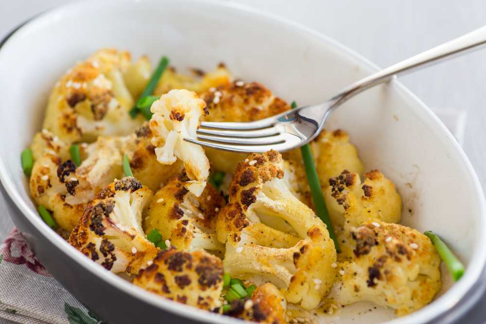 Baked Cauliflower with Green Onion serve in a white baking dish