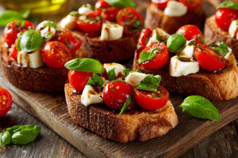 Bruschetta with Cherry Tomatoes, Mozzarella and Balsamic Glaze serve on wooden board