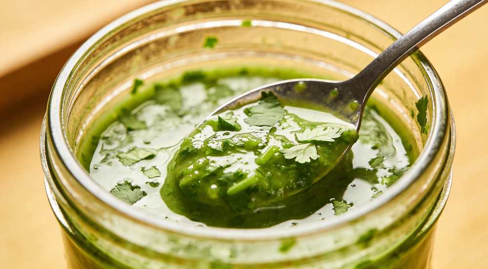 Cilantro Sauce on a spoon in a glass jar