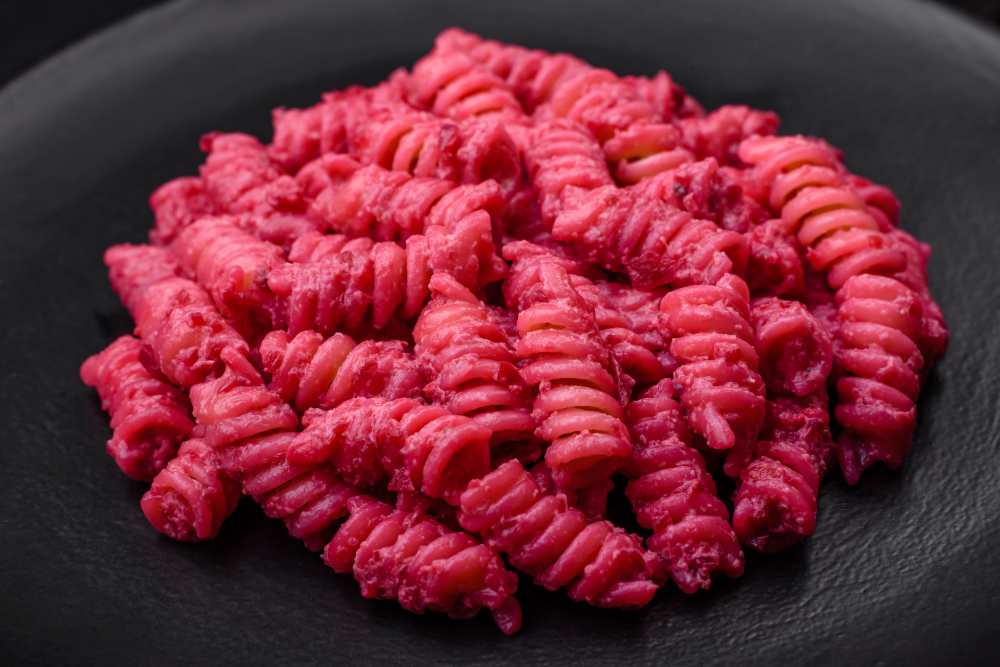 Fusilli Pasta with Beetroot Pesto and Parmesan serve on a black plate