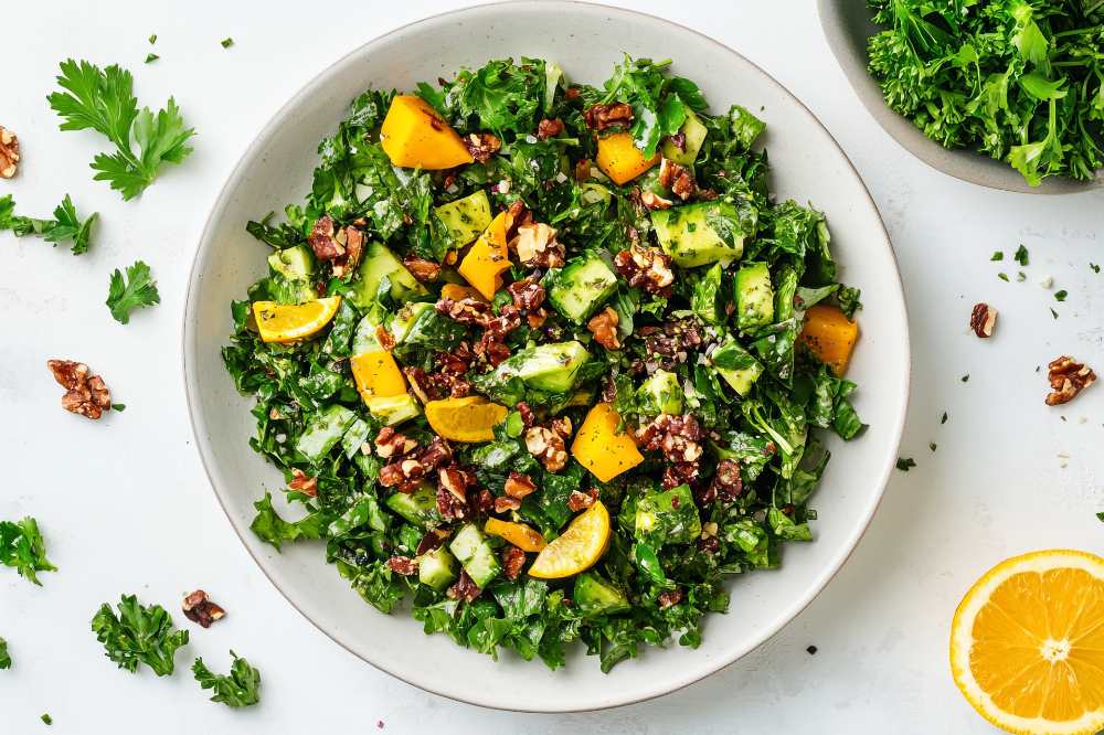 Kale Salad with Butternut Squash, Cucumber and Toasted Walnuts, serve in a white bowl
