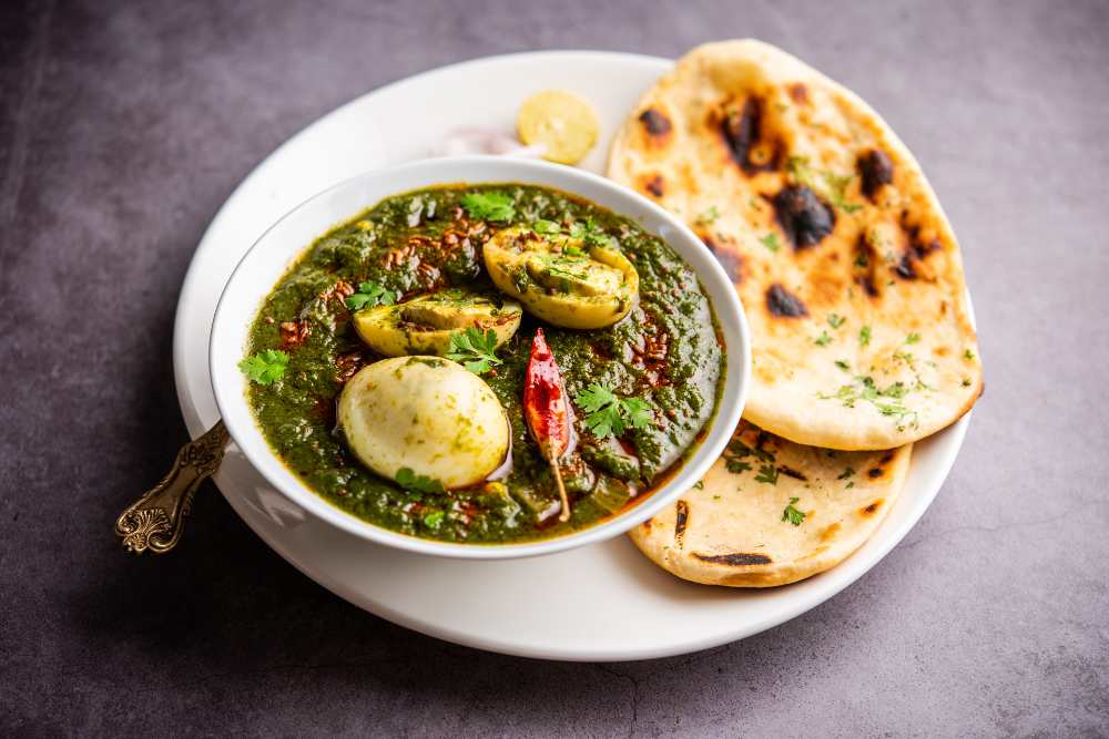 Palak Anda Curry serve in a white bowl with side on naan