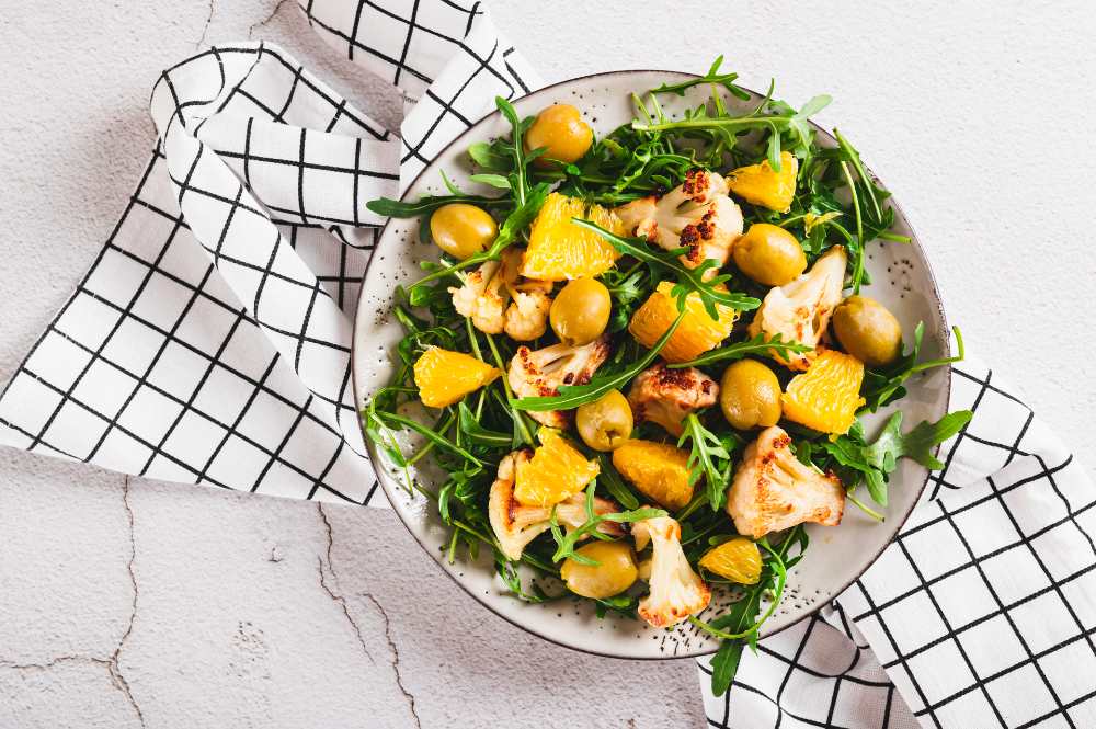 Arugula Salad with Roasted Cauliflower, Orange, and Green Olives, on a plate top view