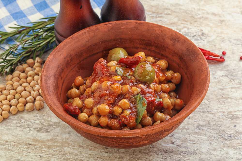 Chickpea beans stew with dry tomato, red chili pepper and green olives
