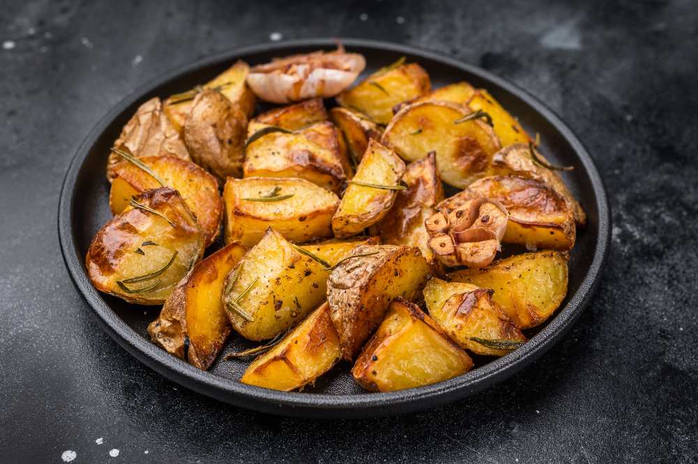 Crispy Skin-On Potatoes with Rosemary on a black plate