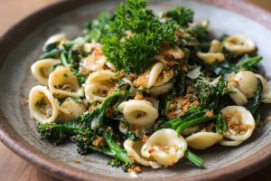 Italian orecchiette pasta mixed with sauteed broccoli rabe garlic and red chili flakes fresh garnish with parsley, serve on a plate