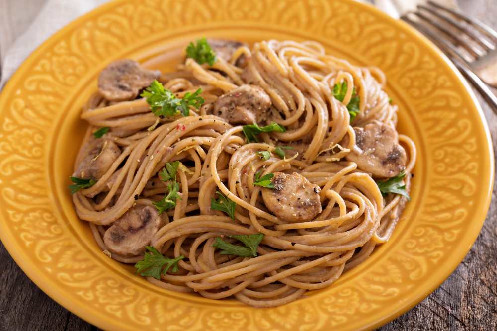 Mushroom whole wheat spaghetti serve in a yellow plate