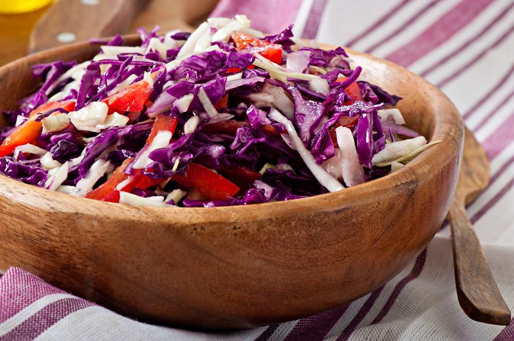 red and white cabbage and sweet red pepper salad, seasoned with lemon juice and olive oil in wooden bowl