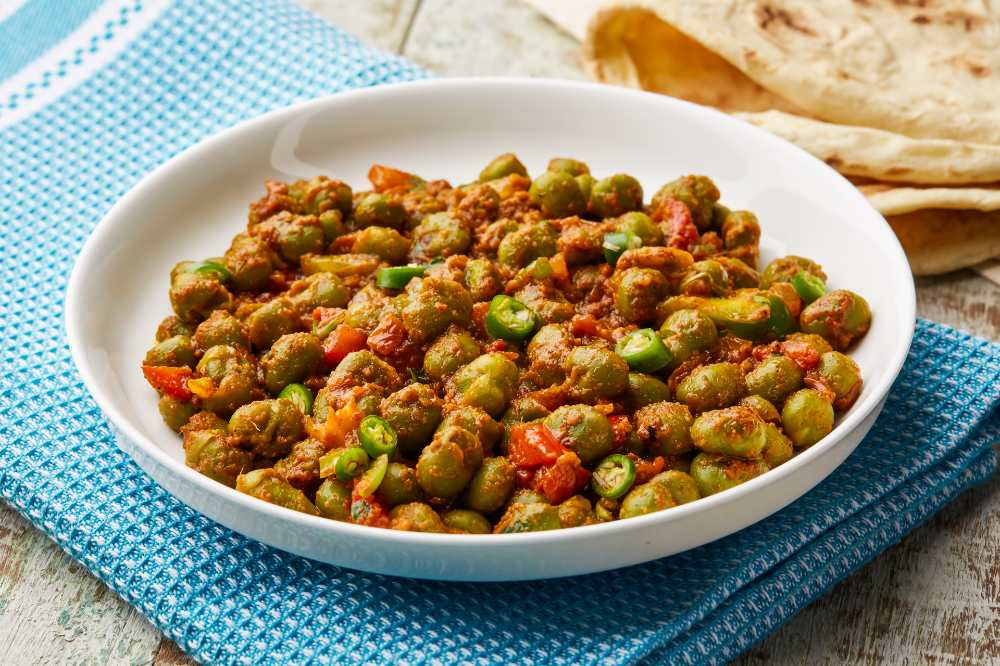 Peas masala orspicy matar green bean with tomato and green chilli served in dish isolated on table top view with a side of Naan.