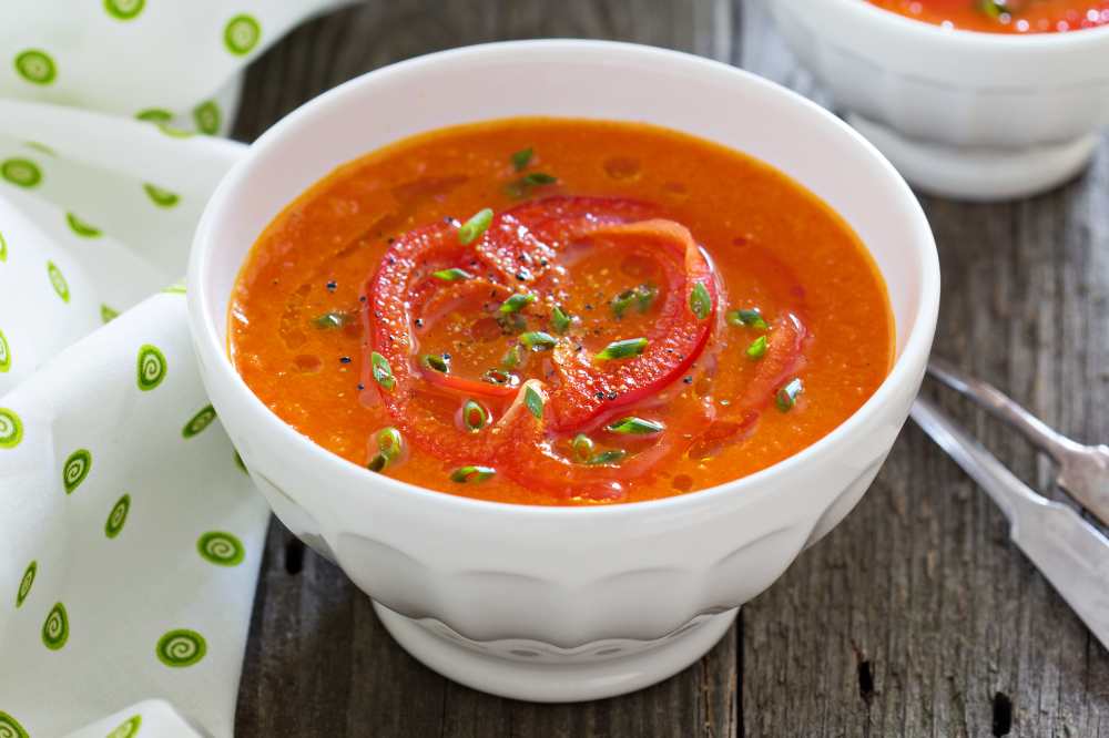 Roasted red pepper soup, top with green onion, serve in white bowl