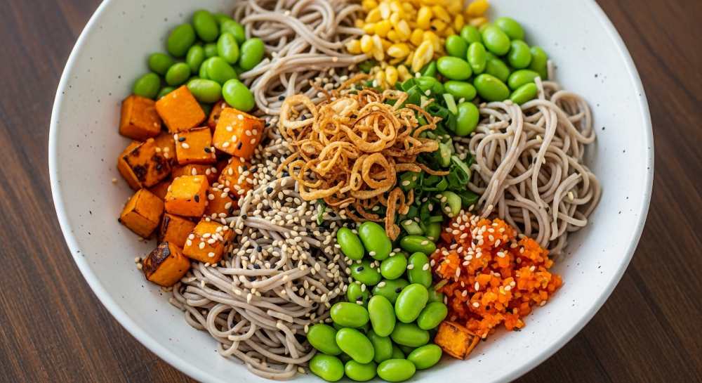 Soba Noodle Bowl with Roasted Sweet Potato, corn, Edamame, top with Crispy Fried Onions , serve in a white bowl
