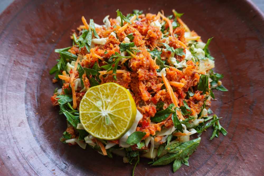 Trancam is a traditional salad from Java, Indonesia made from fresh vegetables such as cucumber, basil, long beans, and white cabbage, which are cut into pieces and mixed with green, serve with half of lemon in a rustic bowl top view