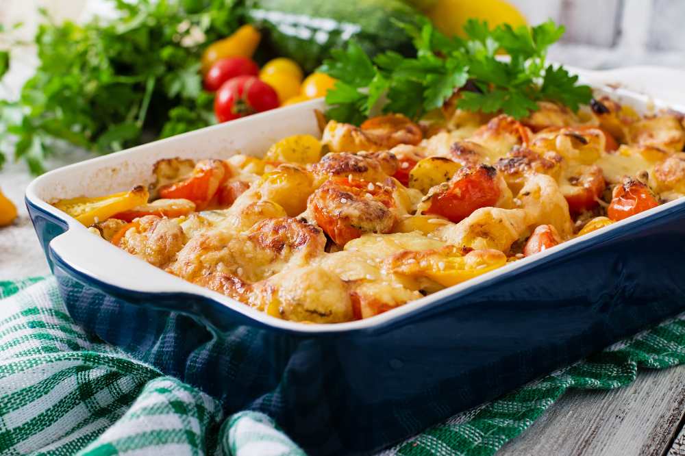 Vegetarian Vegetable casserole with zucchini, mushrooms and cherry tomatoes, serve in a baking dish with parsley on top.