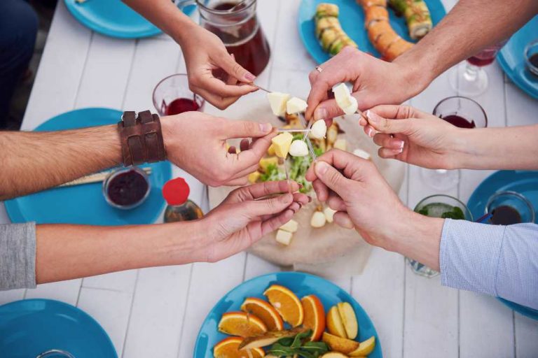 hands reaching toward food over a table