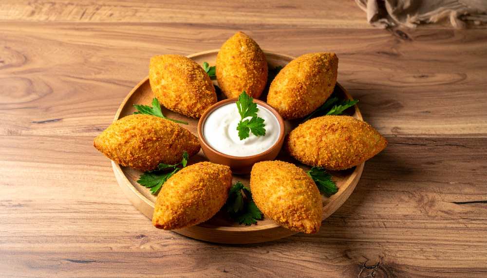 vegetarian kibbeh with side tahini sauce, serve in a round wooden plate