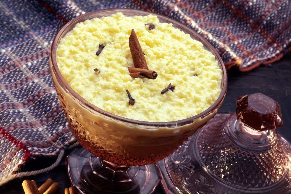 Ambrosia, delicious Portuguese sweet made with eggs and milk, top with a cinnamon stick , serve in a glass bowl on a decor table cloth.