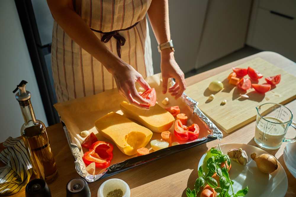 Women preparing veggie in a baking dish, on a kitchen counter top view.