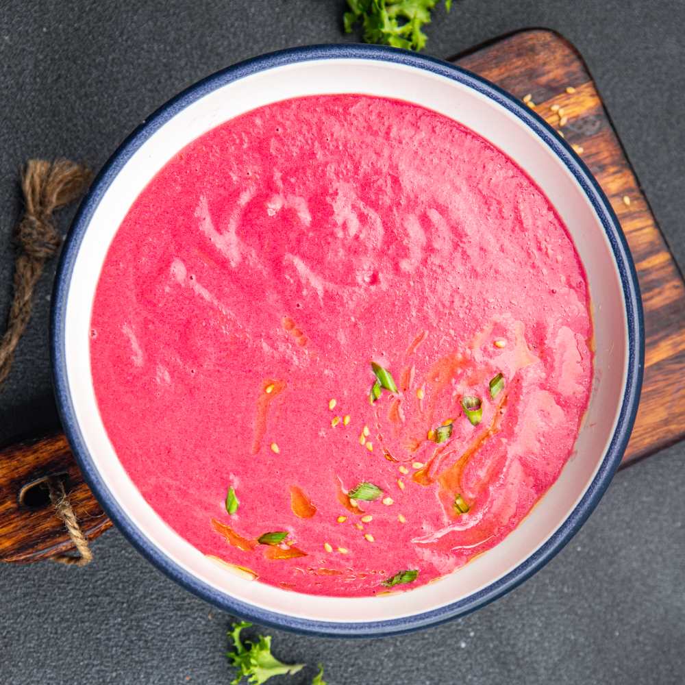 cream soup beetroot beet, leek potatoes, serve in a white plate on a wooden board, close-up top view.