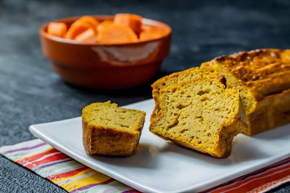 orange carrot cake on a long white plate with side carrot bowl, close-up side view.
