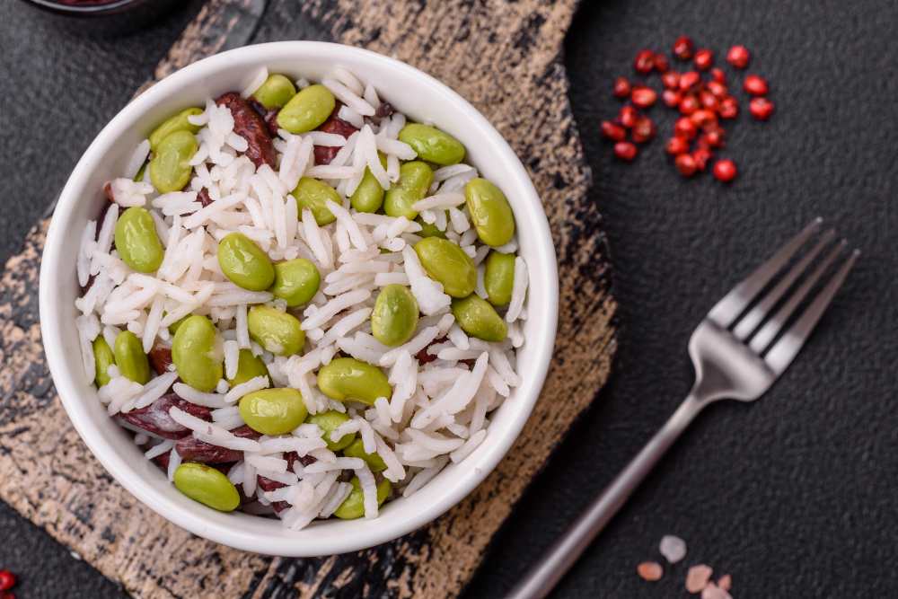 white rice with green edamame and red beans with salt and spices. serve in a white bowl , top view.