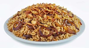 Fried onions and rice, serve on a white plate in a white background, close-up top view.