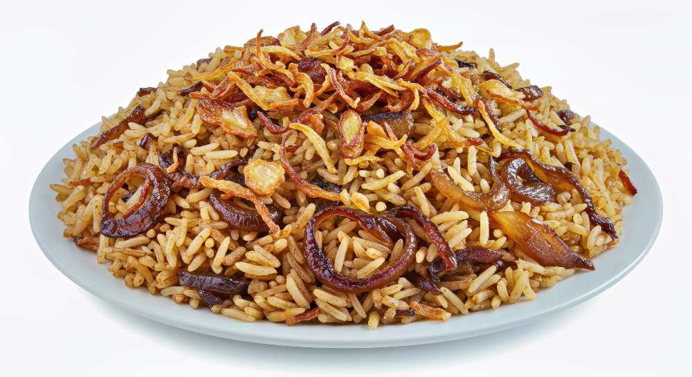 Fried onions and rice, serve on a white plate in a white background, close-up top view.