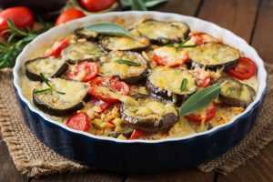Moussaka eggplant casserole, serve in a round baking dish on a table cloth , close-up top view.