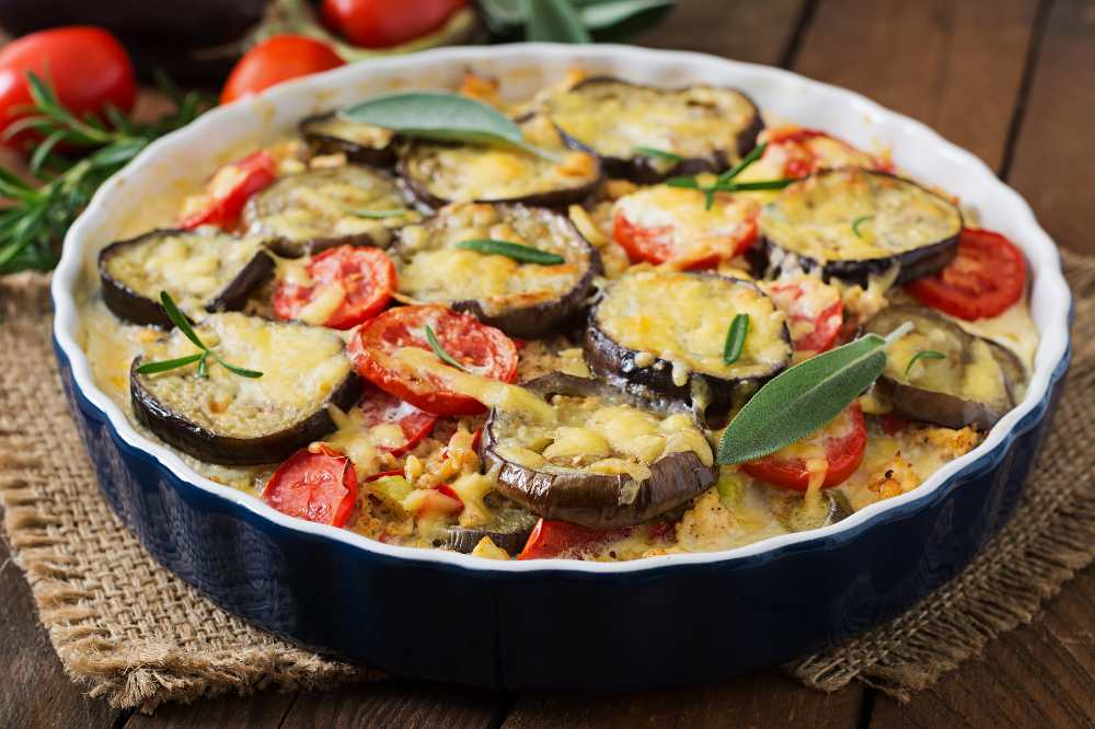Moussaka eggplant casserole, serve in a round baking dish on a table cloth , close-up top view.