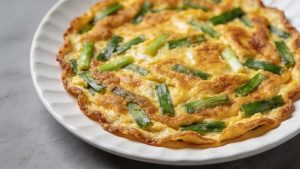 scallions eggs omelet serve in a white plate on a gray rustic counter top, close-up view from the top