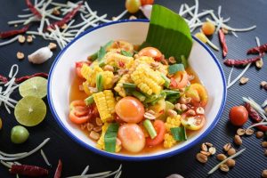 Corn salad food thai menu spicy salad fruit and vegetables herbs and spices ingredients with chili tomato peanut garlic, close up top view.