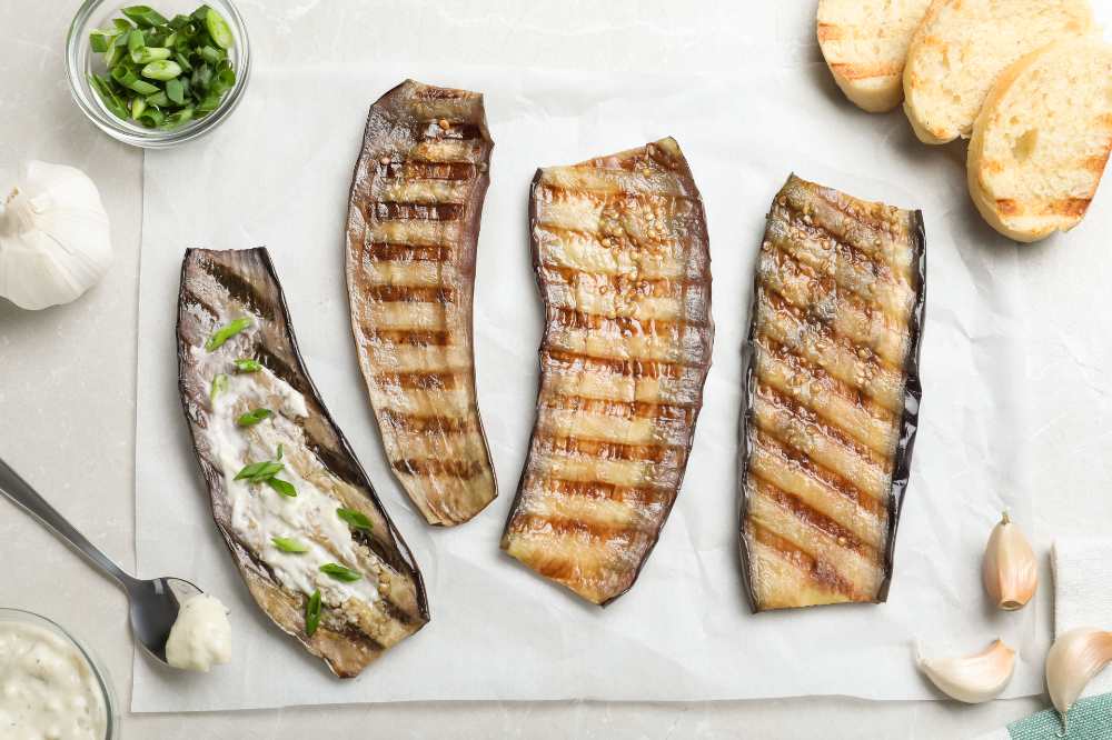 Delicious grilled eggplant slices with sauce on grey table