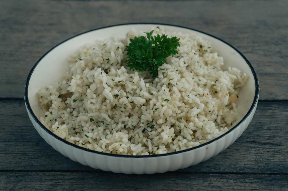 parsley rice, serve in a white bowl on a wooden table , close up top view