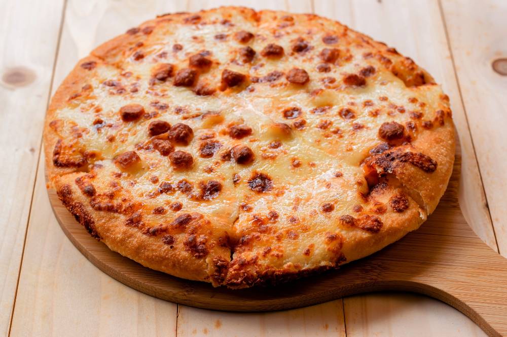 Homemade Cheese Pizza serve on a wooden cutting board close up top view.