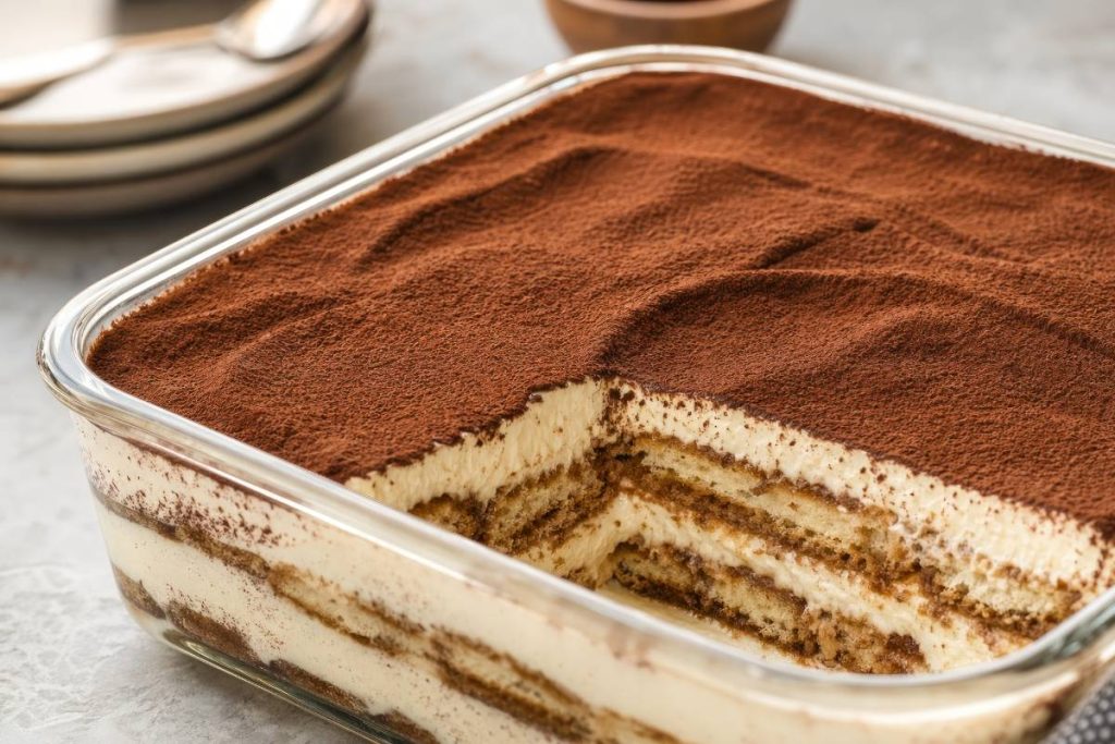 Homemade Layered Tiramisu, serve in a glass baking dish , close up side view.