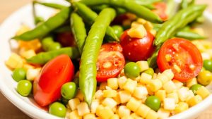 salad with cherry tomatoes, corn, and green beans, serve in a white plate, close up side view.